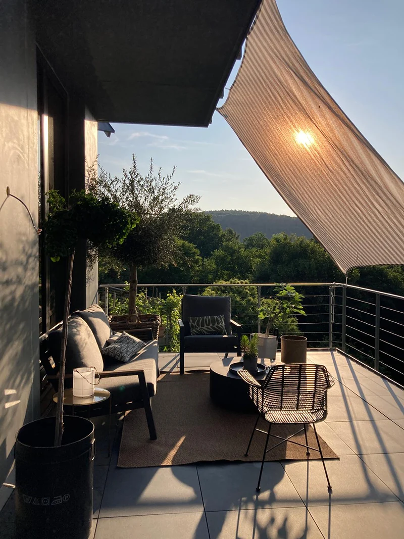 Großzügige Terrasse mit Designmöbeln, Sonnensegel und Blick in die Natur – moderne Architektur mit fließendem Übergang zwischen Innen- und Außenbereich.
